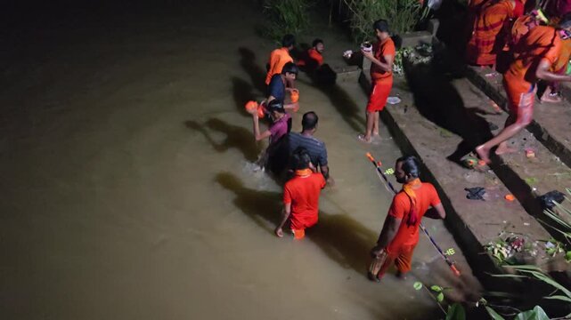 Authentic overhead footage of Kanwariya devotees collecting holy water from a River during the sacred Kanwar Yatra in the holy month of Shravan Sawan, India. Dressed in traditional saffron attire