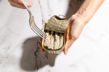 Female hands eating sardines on kitchen countertop background