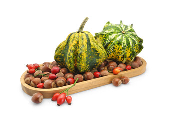 Decorative pumpkins, hazelnuts, and ripe rose hips on wooden tray. Autumn fruits isolated on white background. Harvest theme, natural home decor.