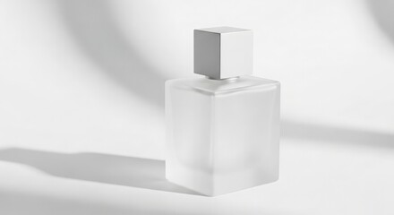 A frosted glass perfume bottle with a square cap sits on a white surface, casting a shadow with soft, blurred light patterns in the background.