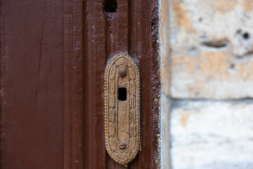 An old metal keyhole on a wooden door