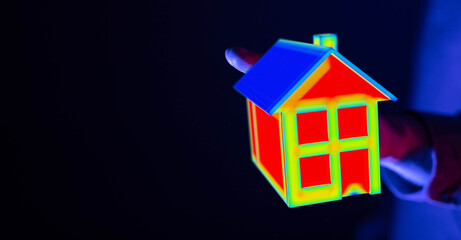 Naklejka premium Image of a hand holding a miniature colorful house, symbolizing energy efficiency, home inspection, thermal imaging, and property investment. Id