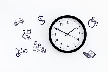 Wall clock and many paper cards with hand drawing of different life activities, top view. Time management concept. Life balance and planning concept.