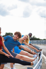 Fototapeta premium Smiling group of people are preparing for running together talking and stretching on outdoor road.