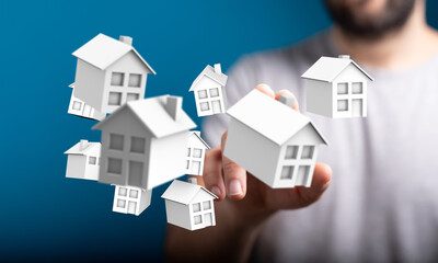 Conceptual image of a hand reaching towards small house models, representing concepts like real estate, property investment, and home ownership.