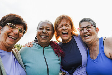 Multiracial senior women having fun together after yoga class outdoor in city park - Healthy lifestyle and mature people concept - Main focus on latin center woman face