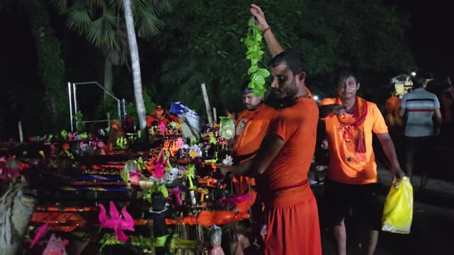 Authentic documentary footage of Kanwariya devotees gathering at a riverbank during the sacred Kanwar Yatra in India. Wearing traditional saffron clothing and carrying decorated Kanwars