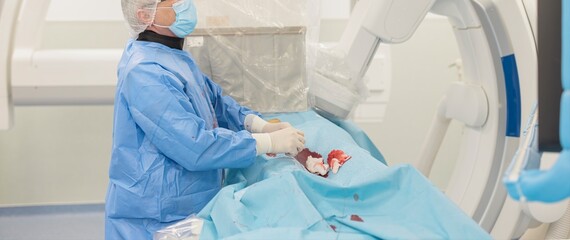 A medical professional in protective gear is preparing for an advanced liver tumor treatment, using specialized microspheres to effectively target blood vessels