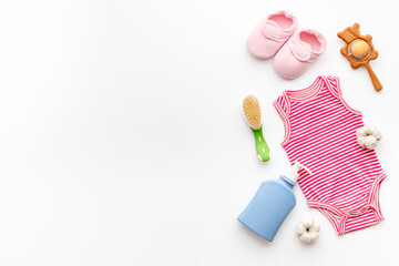 Set of baby hygiene cosmetic products - shampoo and soap with a comb. Eco friendly accessories - bodysuit and wooden toys with bottle of milk on white background, top view