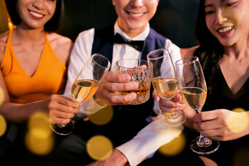 Beautiful woman having fun with group of friends clinking champagne glasses during celebration party. Drink concept.