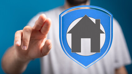 A person's finger pointing at a house icon on a shield, representing home security and protection,...