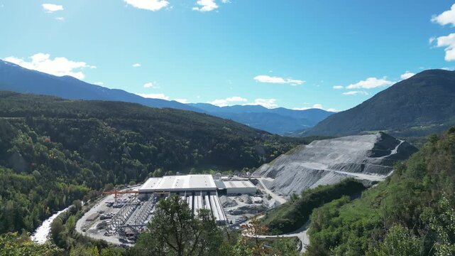 The Brenner Base Tunnel "BBT" construction site in Varna, Alto Adige, with cranes and machinery set against the stunning backdrop of the Alps.