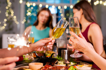  Beautiful woman having fun with group of friends clinking champagne glasses during celebration party. Drink concept.