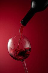 Pouring red wine from a bottle into a glass.