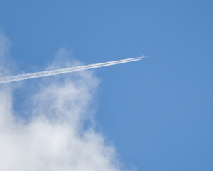 Jet is flying through the sky with a white contrail behind it
