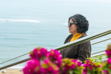 A woman is standing on a railing overlooking the ocean