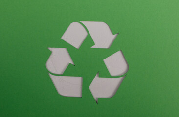 A crisp, clean shot of a paper cutout recycling symbol against a vivid green background. Great for themes like recycling, waste management, envi