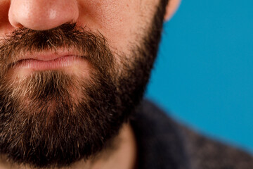 Obraz premium Closeup of a man's beard and facial features against a vibrant blue background, perfect for grooming and lifestyle concepts. Shows texture and d