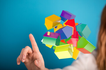 Abstract image of colorful 3D houses interacting with a human hand, perfect for real estate,...