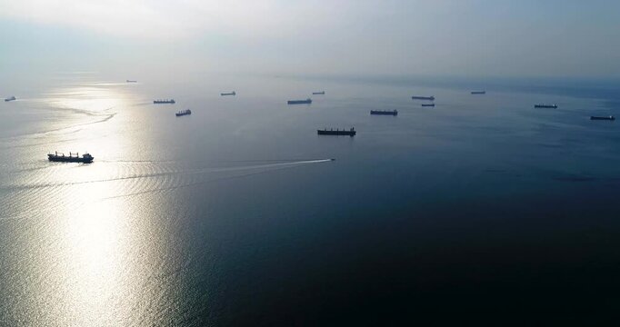 Ships in roadstead of Novorossiysk. A large number of ships are sailing in the ocean. The sky is cloudy and the sun is shining on the water