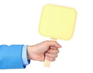 A person's hand grips a small, square sign, holding it against a stark black backdrop