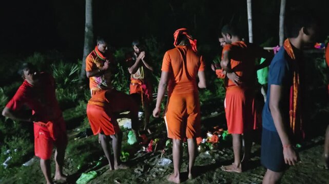 Authentic documentary footage of Kanwariya devotees gathering at a riverbank during the sacred Kanwar Yatra in India. Wearing traditional saffron clothing and carrying decorated Kanwars