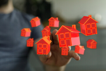 Person's hand interacting with virtual houses, symbolizing real estate, property investment, and the digital home.