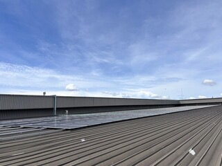 Solar panels installed on a large industrial warehouse roof under a bright blue sky, emphasizing renewable energy and sustainable power generation.