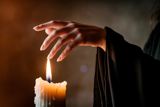 Hand above flickering candle flame. A moment of witchcraft, mystery, and feminine power