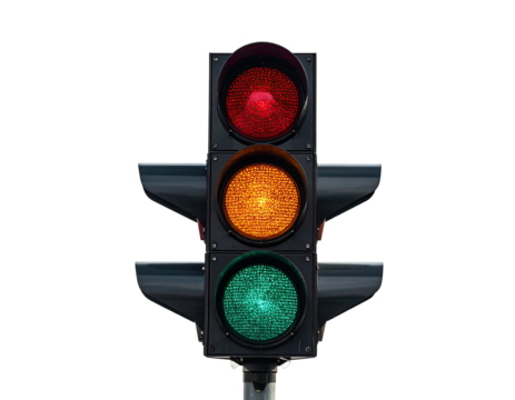 A traffic light, red, yellow, and green, against a stark black background