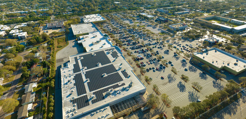 Solar power plant with blue photovoltaic panels mounted on commercial shopping store building roof for producing green ecological electricity. Production of sustainable energy concept