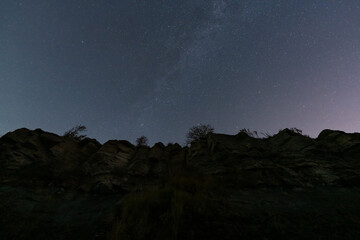 Starry night sky with the Milky Way galaxy over a dramatic rocky cliff on the Paldiski peninsula in Estonia.