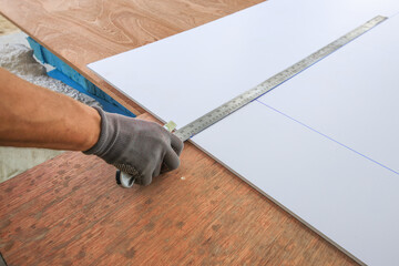 Man is using a ruler to measure a piece of wood