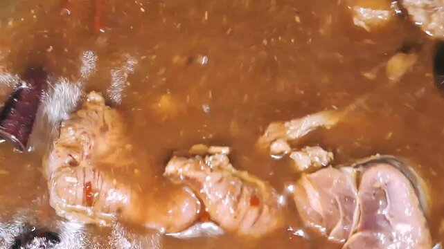 A close-up of brown beef broth being stirred in a pot after the addition of rich spices and seasonings, part of the cooking process for Semur Daging, a traditional Indonesian beef stew.