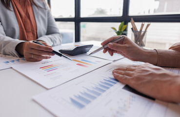 Group of confident business people point to graphs and charts to analyze market data, balance sheet, account, net profit to plan new sales strategies to increase production capacity.	