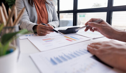 Group of confident business people point to graphs and charts to analyze market data, balance sheet, account, net profit to plan new sales strategies to increase production capacity.	