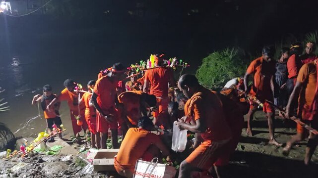 Authentic documentary footage of Kanwariya devotees gathering at a riverbank during the sacred Kanwar Yatra in India. Wearing traditional saffron clothing and carrying decorated Kanwars