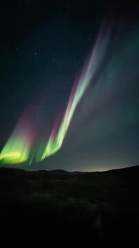 glowing northern lights dancing in night sky, colorful aurora borealis with green and purple waves, starry backdrop, dreamy natural landscape, loop animation for background use.