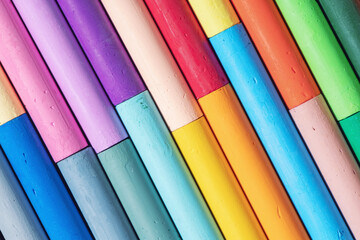Bright background made of colorful oil pastels arranged in diagonal lines. Close-up of vivid artistic crayons in various shades, symbol of creativity, art and education.