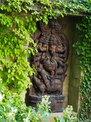 Wooden sculpture of Ganesha surrounded by ivy