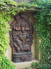 Carved wooden Ganesha statue surrounded by ivy leaves