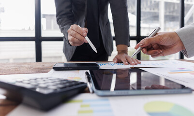 Two colleagues engaged in business analytics, using digital tablets over financial charts. Colleagues Collaborating with Tablets on Business Analytics.


