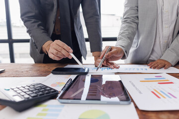 Two colleagues engaged in business analytics, using digital tablets over financial charts. Colleagues Collaborating with Tablets on Business Analytics.

