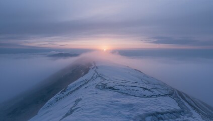 Stunning scene of a foggy dawn over a snowy peak.