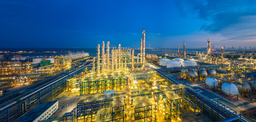 Panoramic view of a sprawling coastal oil refinery and industrial complex at night.