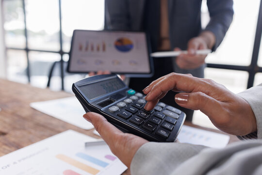 Colleagues engaged in business team analytics, using digital tablets over financial charts. Colleagues Collaborating with Tablets on Business Analytics.
