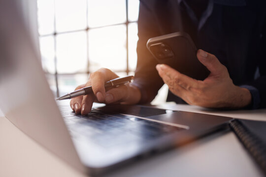 Business man pen in hand and mobile phone, online working at office. Student studying online, surfing the internet, searching the information, e-learning, business technology
 - Powered by Adobe