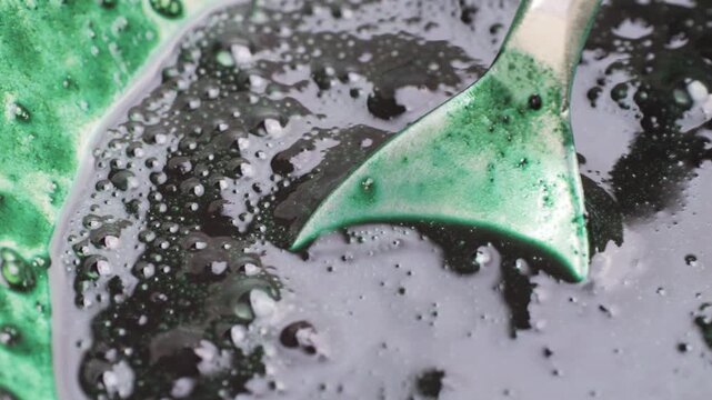 Green chlorella algae powder on a wooden spoon, top view. Healthy nutritional supplement.