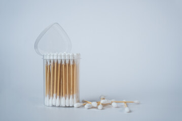 Transparent glass jar filled with white cotton swabs on a clean white background. Minimalistic home decor or hygiene concept in soft natural light. 