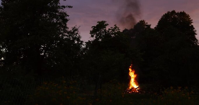 Cosy campfire burning in the garden at sunset. Concept of camping, warmth, relaxation, and outdoor leisure.